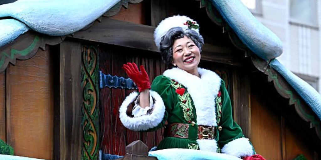Lainie Sakakura, a Japanese-American dancer, is this year's Mrs. Claus. She wears a green, ornate robe with red gloves and a white hat.