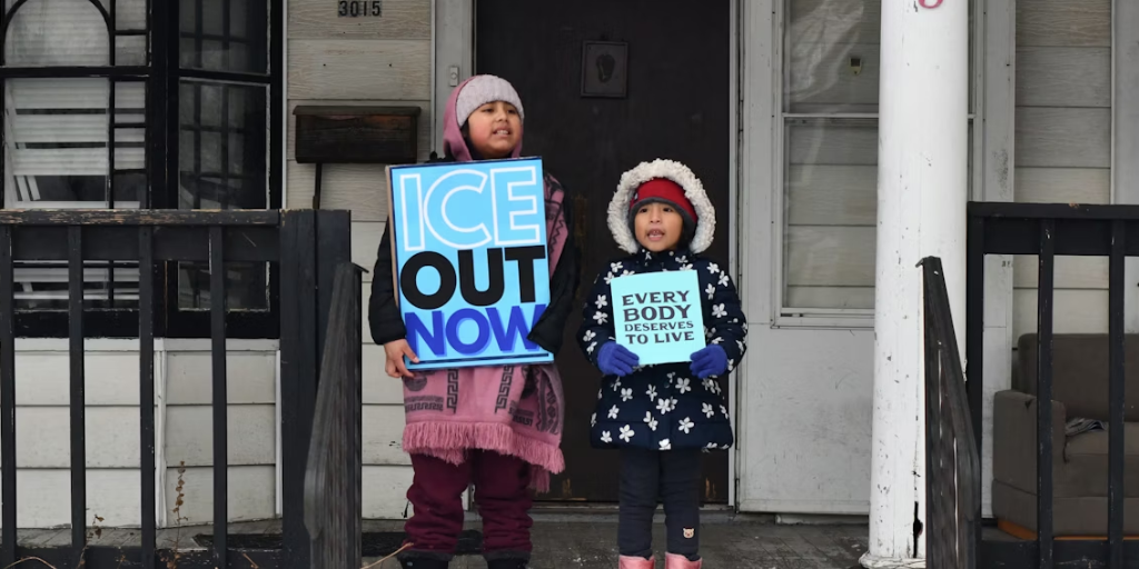 Children hold up anti-ICE protest signs.