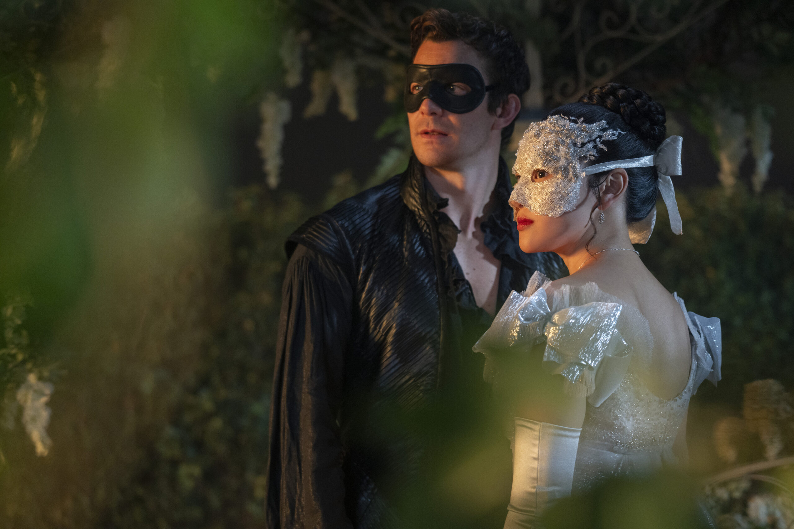 Bridgerton. (L to R) Luke Thompson as Benedict Bridgerton, Yerin Ha as Sophie Baek in episode 401 of Bridgerton. Benedict wears a black shirt and mask, and Sophie wears a silver dress and mask.