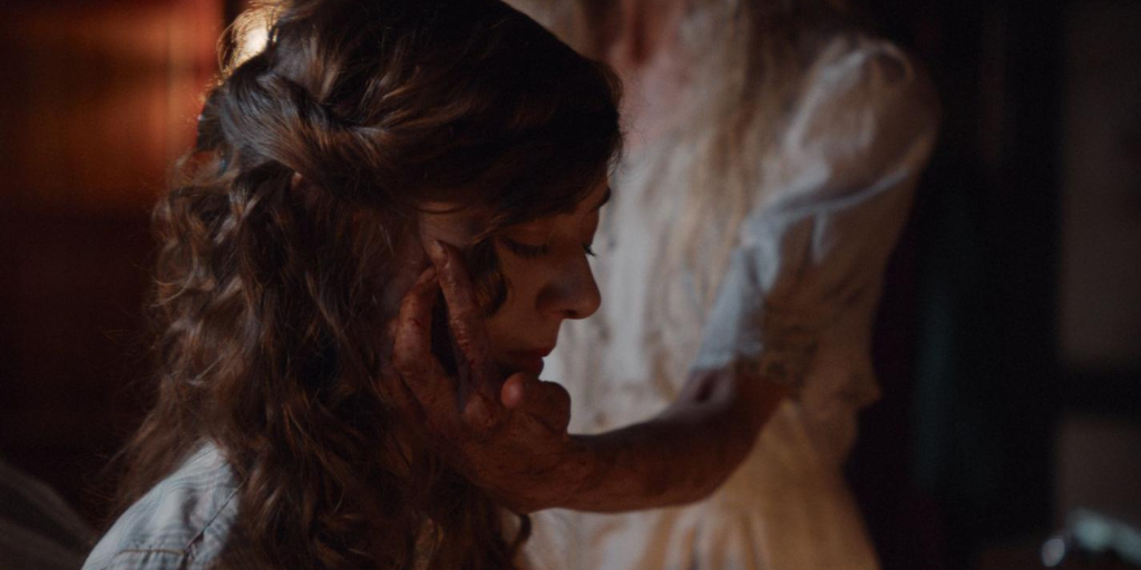 Virginia (Danika Golombek) writes while being visited by a mysterious female figure (Nathalie Söderqvist). (Photo credit: Storyboard Media)