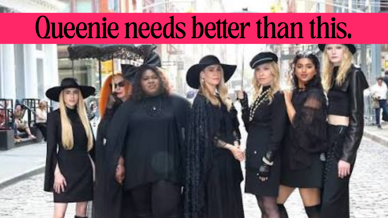The leaked image from American Horror Story 13, with the cast in black witchy, fashionable garb. But Queenie's clothes looks a bit more drab. Text over the top in a pink bar reads: Queenie needs better than this."